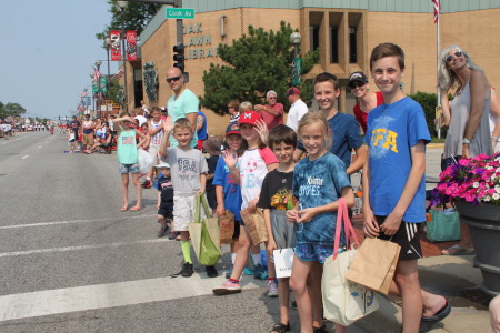 Children line 95th Street with bags in hand ready to scoop up the free candy tossed by parade marchers