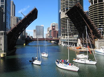 A small flotilla of boats passes through the o...