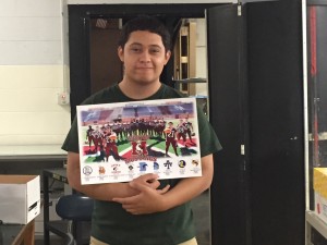 Anthony Valdoviños (Morton West, Class of 2016) displays the football poster he created. Valdoviños, also the lead designer of the 2015 Varsity Baseball poster, is the first student with two designs selected for publication.